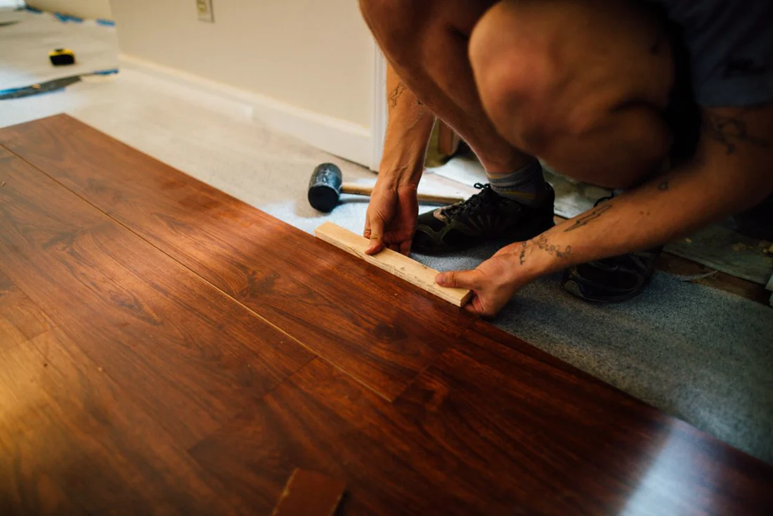 Pose d'un parquet flottant sur sous-couche, maillet en main